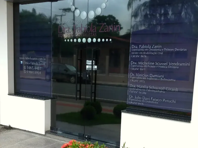 Fachada envidraçada com o nome Fabíola Zanin e flores na frente
